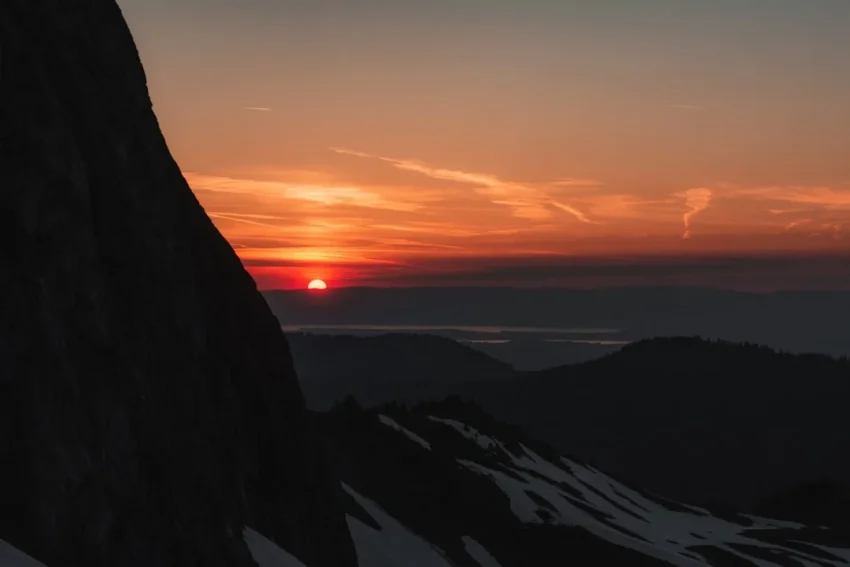 Build Confidence concept shown as a person standing on a mountain at sunrise